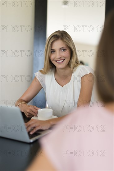 Caucasian women using laptop and drinking coffee