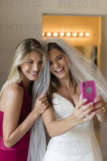 Caucasian bride and bridesmaid taking selfie