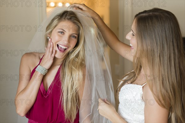 Caucasian bridesmaid wearing veil of bride