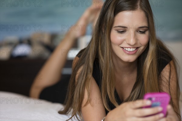 Caucasian woman using cell phone on bed