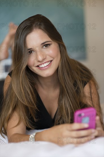 Caucasian woman using cell phone on bed