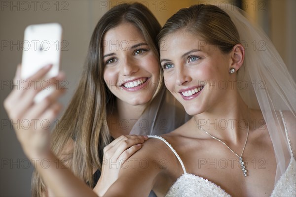 Caucasian bride and bridesmaid taking selfie