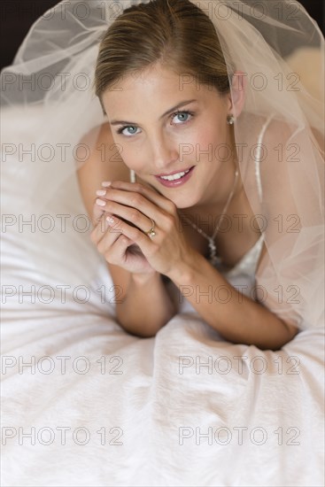 Caucasian bride in wedding veil laying on bed