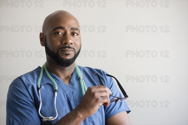 Black nurse holding eyeglasses