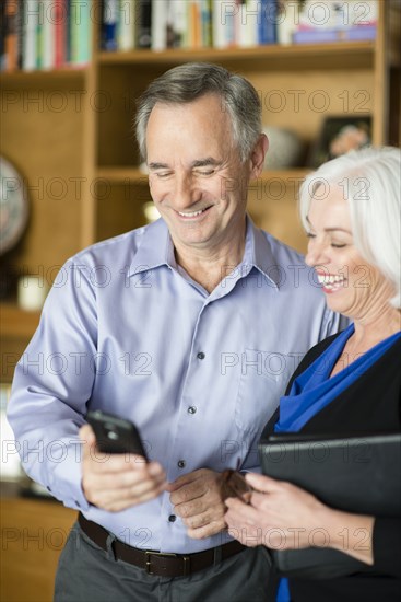 Caucasian couple using cell phone in living room