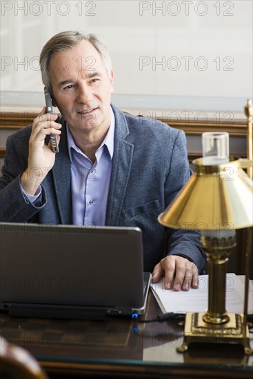 Caucasian businessman talking on cell phone at desk