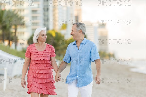 Older Caucasian couple walking on beach