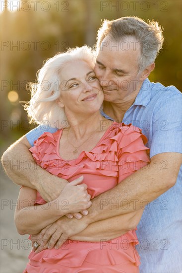 Older Caucasian couple hugging on beach
