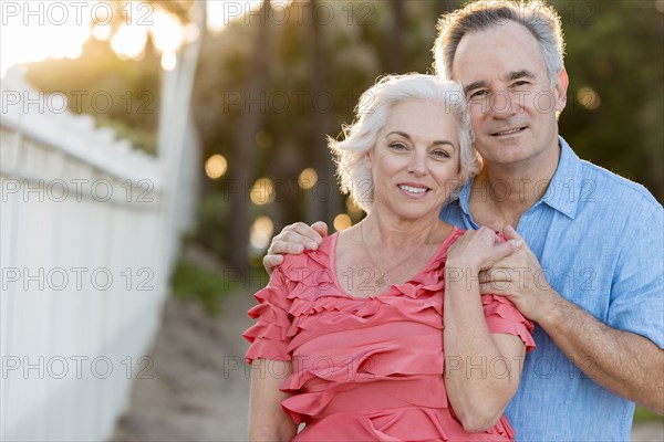 Older Caucasian couple hugging on beach