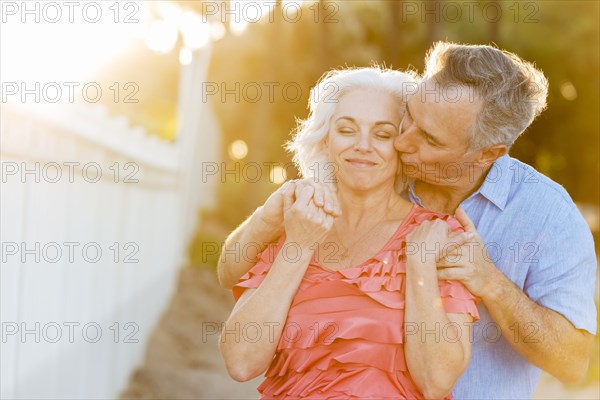 Older Caucasian couple kissing on beach