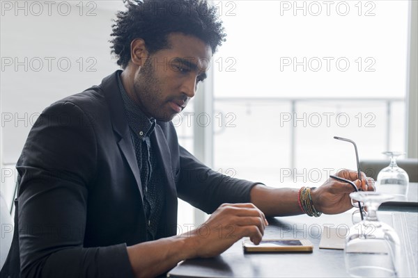 Hispanic businessman using cell phone at conference table