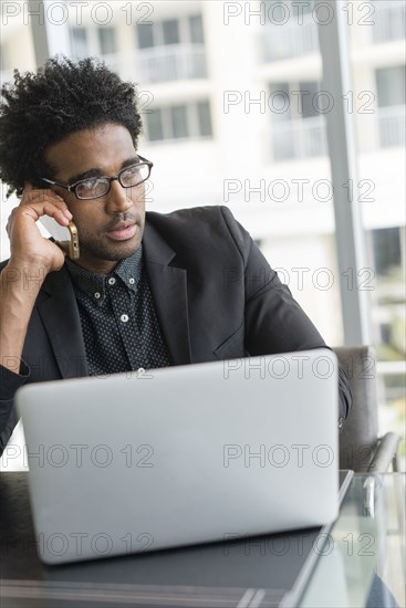 Hispanic businessman talking on cell phone in office