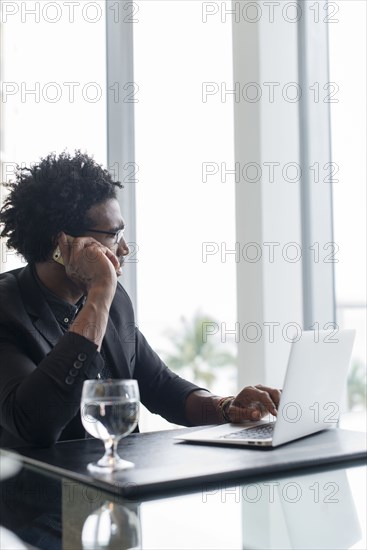 Hispanic businessman using cell phone and laptop in office