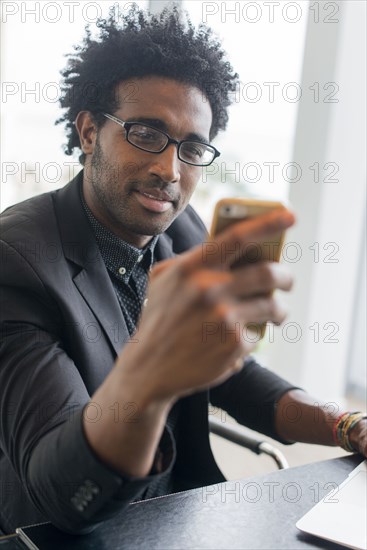 Hispanic businessman using cell phone in office