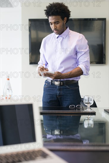 Hispanic businessman writing notes at conference table