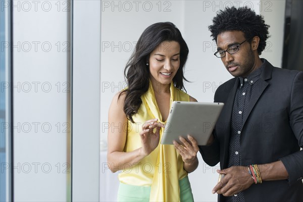 Hispanic business people using digital tablet in office