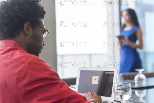 Hispanic businessman using laptop at conference table