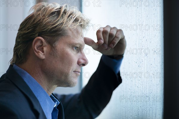 Caucasian businessman standing at rainy office window