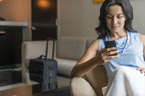 Hispanic businesswoman using cell phone in office lobby