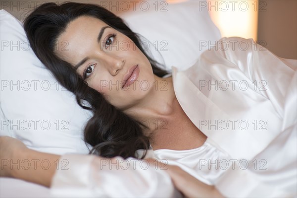 Hispanic woman wearing lingerie in bed