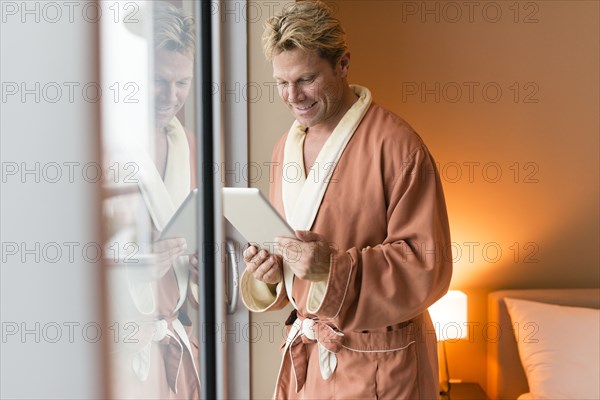 Caucasian man using digital tablet at bedroom window