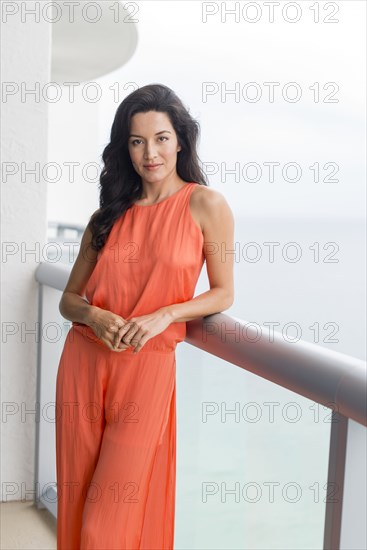 Hispanic woman leaning on balcony