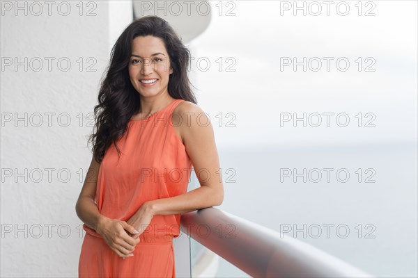 Hispanic woman leaning on balcony