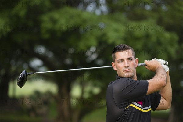 Caucasian man swinging club on golf course