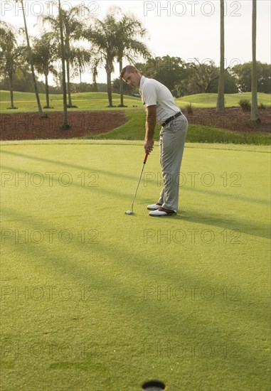 Caucasian man putting on golf course