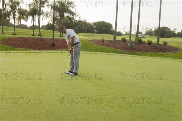 Caucasian man putting on golf course