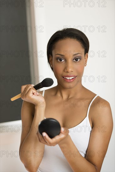 Mixed race woman applying makeup