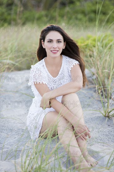 Hispanic woman sitting on beach