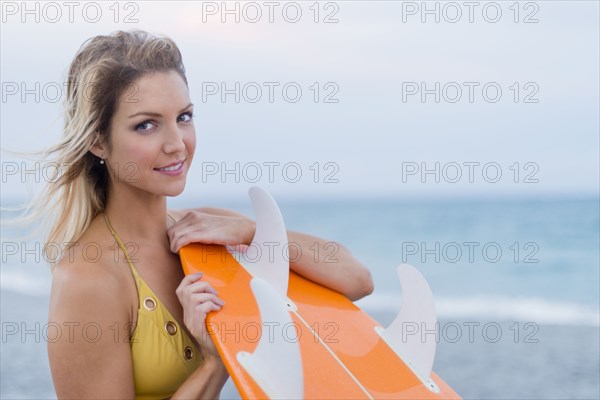 Caucasian woman holding surfboard on beach