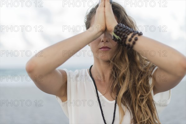 Hispanic woman meditating on beach