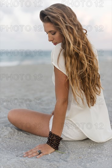 Hispanic woman sitting on beach