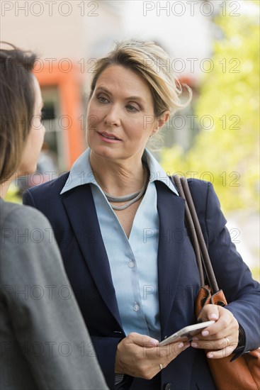 Caucasian businesswomen using cell phone outdoors