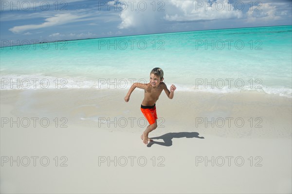 Hispanic boy running on beach