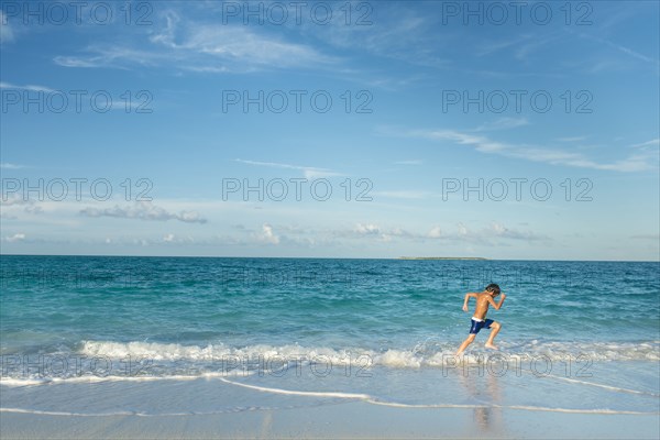 Hispanic boy running on beach