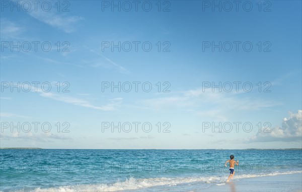 Hispanic boy running on beach