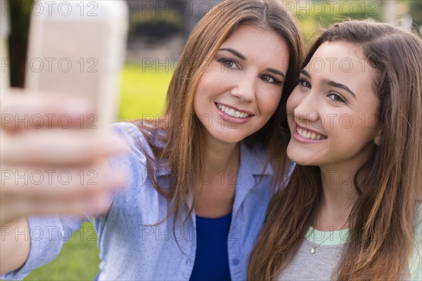 Mother and daughter taking selfie outdoors