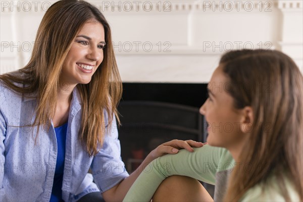 Mother and daughter talking near fireplace