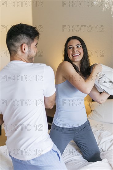 Hispanic couple having pillow fight