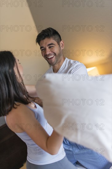 Hispanic couple having pillow fight