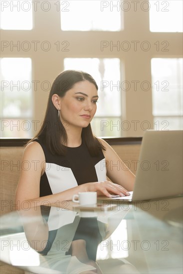 Hispanic businesswoman using laptop in office