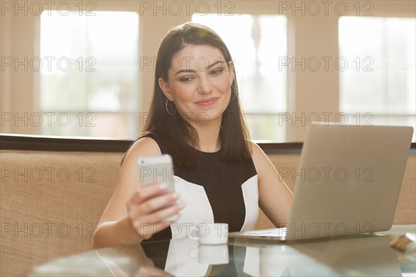Hispanic businesswoman using cell phone in office