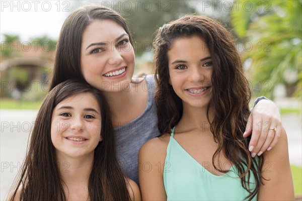 Mother and daughters smiling outdoors