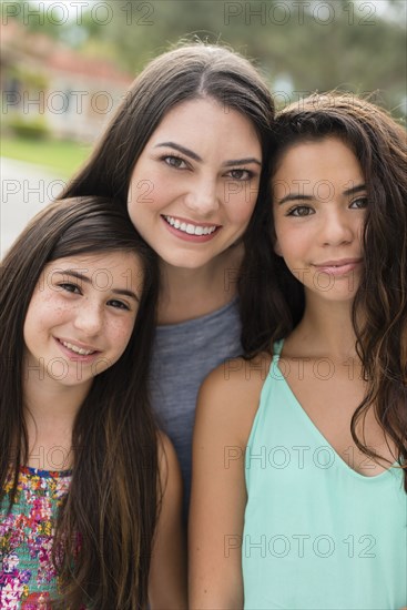 Mother and daughters smiling outdoors