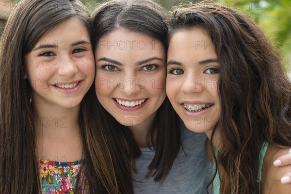 Mother and daughters smiling outdoors