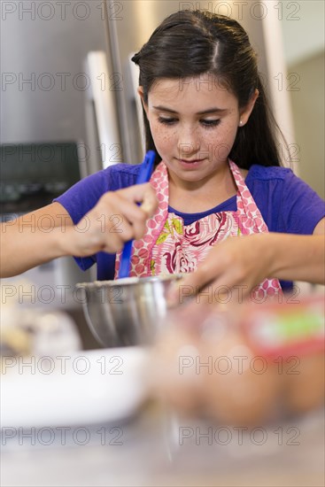 Mixed race girl baking in kitchen