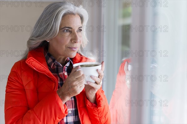 Caucasian woman drinking coffee in window